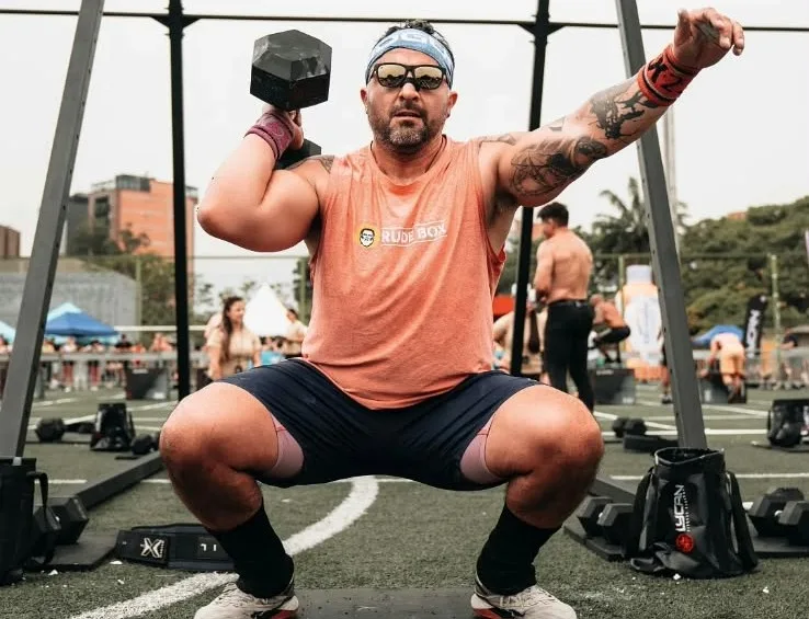 Kris Ojeda con una mancuerna sobre el hombro en competencia